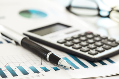 Calculator, graphs on paper and pen on desk